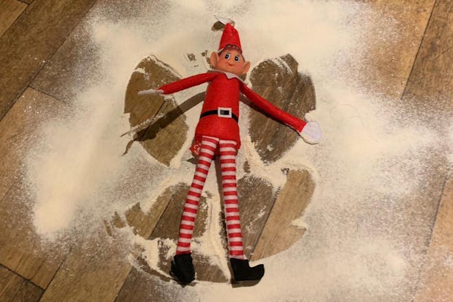 Christmas Elf on the shelf making snow angel in flour on floor