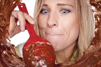 woman eating cake mix with red spoon