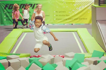 Young boy jumping off trampoline into foam pit