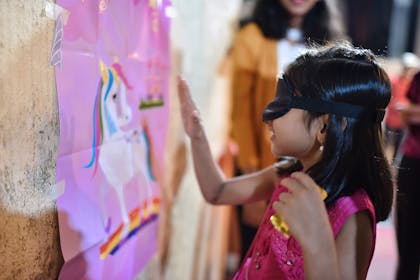 Young girl playing pin the tail on the unicorn