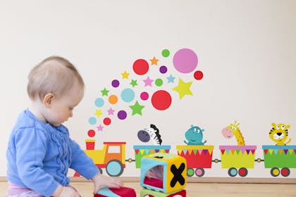 Toddler playing with soft building blocks, with animal wall stickers on the wall.