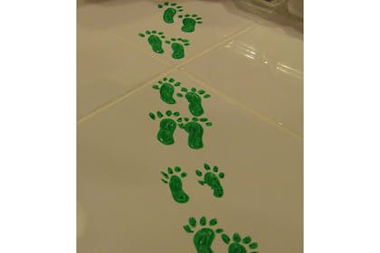 Green leprechaun footprints drawn onto bathroom floor with washable marker pen