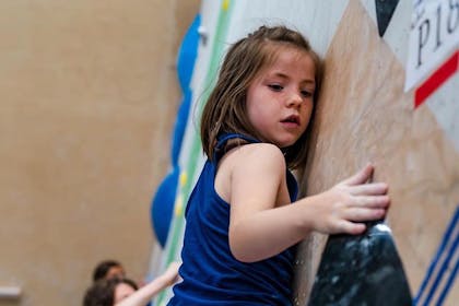 A young girl in a dark blue vest concentrates on a climbing wall at Big Rock Hub, Sheffield