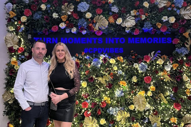 two people infront of a flower wall