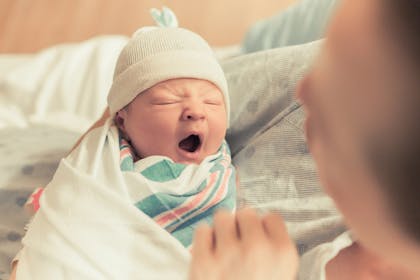Swaddled newborn baby yawning