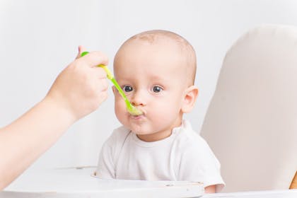 Baby in highchair eating from a spoon