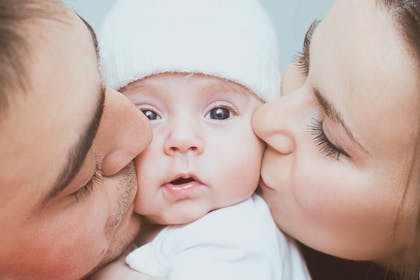 parents kissing baby on the cheek