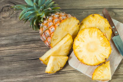 Pineapple being sliced on chopping board