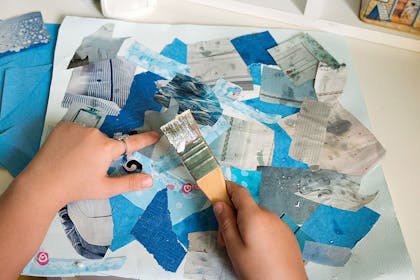 Child making collage from recycled paper and magazines