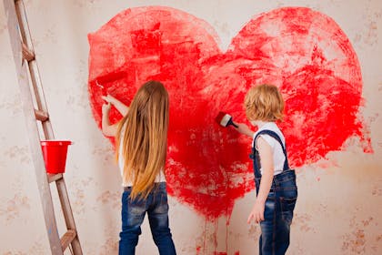 Kids paint red heart on wall