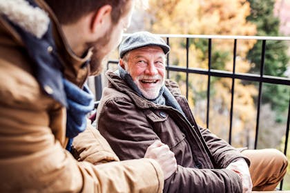 Older man and younger man laughing together outside