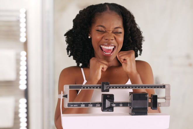 Woman on scales smiling about weight loss