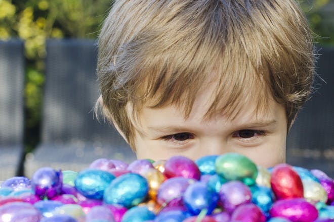 Child looking at lots of small Easter eggs