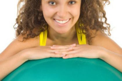 smiling woman leaning on exercise ball