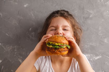 Little girl eating big veggie burger