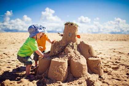 Two toddlers making huge sandcastle