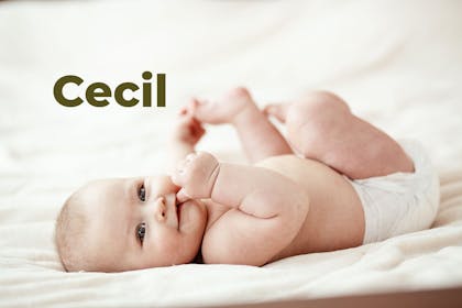 Baby in nappy lying on back holding foot. Name Cecil written in text