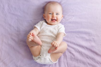 cute smiling baby pictures from above on lavendar sheet