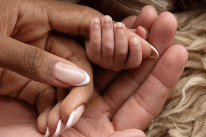 Baby's hand clasps woman's finger