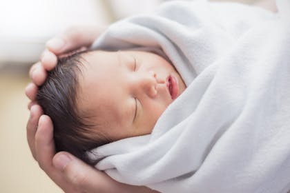 Newborn baby held in parents' hands 
