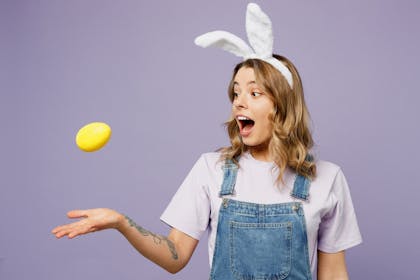 Girl wearing bunny ears tossing an Easter egg