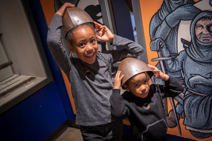 Two sisters in Newcastle Story gallery try on Norman helmets.