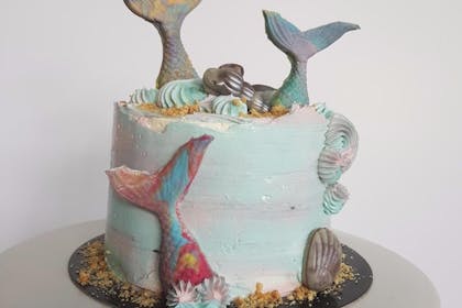 Blue marble birthday cake with sugar topper mermaid tails and shell decorations