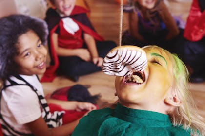 child eating doughnut from string