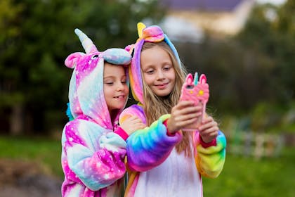Two girls taking a selfie wearing unicorn onesies