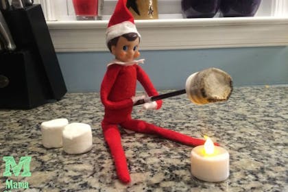 Elf on the Shelf roasting marshmallows over a battery-operated tea light