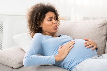 Pregnant woman practising breathing techniques for labour lying down on a sofa