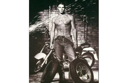 Topless man posing with tyres