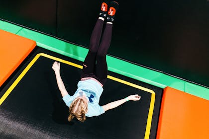 Girl jumping backwards onto trampoline
