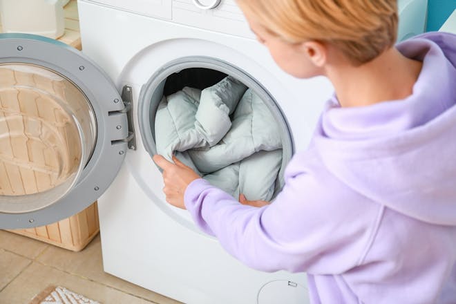 woman putting winter coat in washing machine