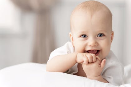 Smiling baby chewing fingers