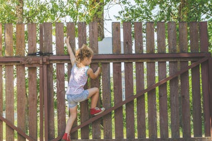 Girl climbing garden fence
