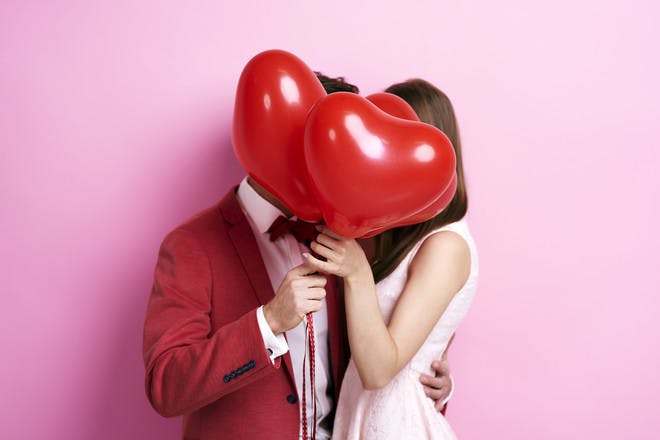 Couple behind love heart balloon