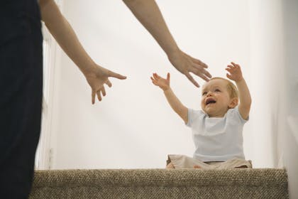 Baby with separation anxiety holding up arms to be picked up