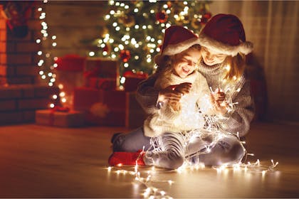 Mother and daughter sat on the floor with Christmas fairy lights