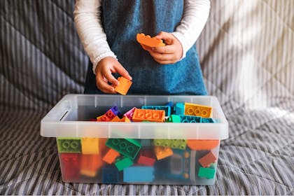 Kid tidying and organising box of toy bricks