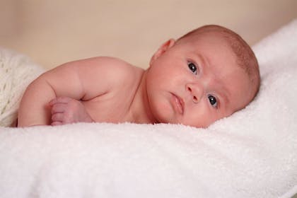 Young baby lying on their side with open eyes