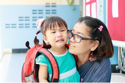 Mum saying goodbye to crying daughter at childcare