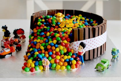 Chocolate cake covered in M&Ms decorated with Paw Patrol figures