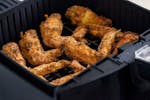 golden chicken wings in an air fryer basket illustrating how to make wings in an air fryer