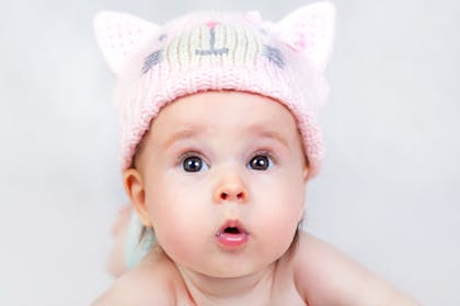 Baby with a surprised expression wearing a kitty hat