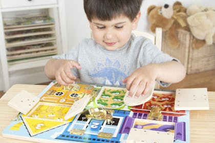 boy playing with Melissa & Doug latches board