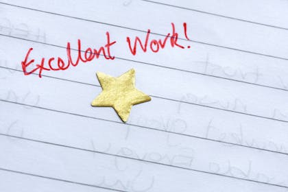 'Excellent work' written in red pen on lined paper with a gold star
