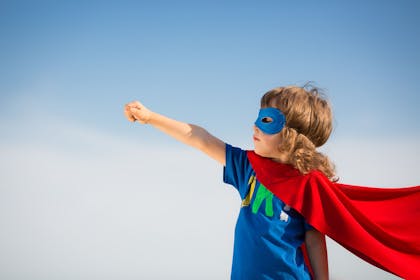 Young boy with superhero's cape and mask