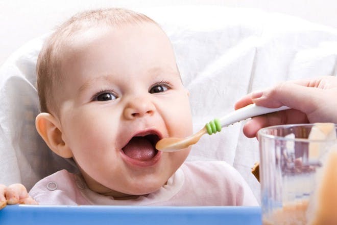 woman feeding baby with spoon