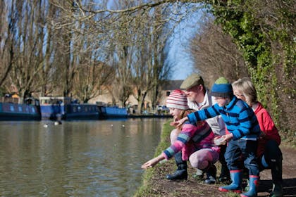 family feeding ducks at a canal